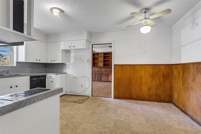 kitchen featuring a sink, white cabinets, wall chimney range hood, light floors, and dishwasher