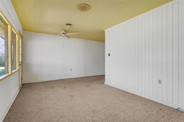 carpeted empty room featuring wooden ceiling and a ceiling fan