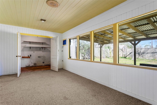 unfurnished bedroom featuring multiple windows, wooden ceiling, and carpet flooring