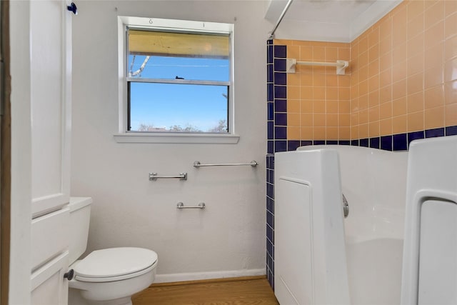 bathroom with a shower with shower curtain, toilet, wood finished floors, and baseboards