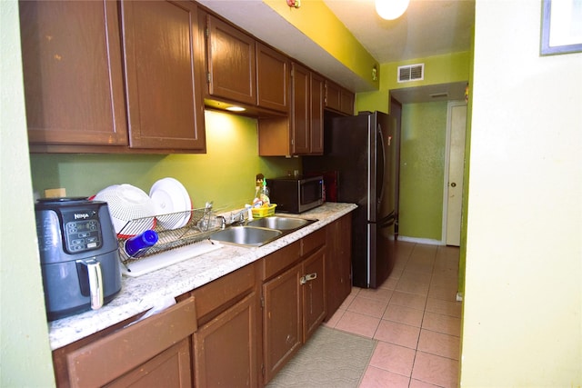 kitchen featuring stainless steel microwave, visible vents, light countertops, light tile patterned flooring, and a sink