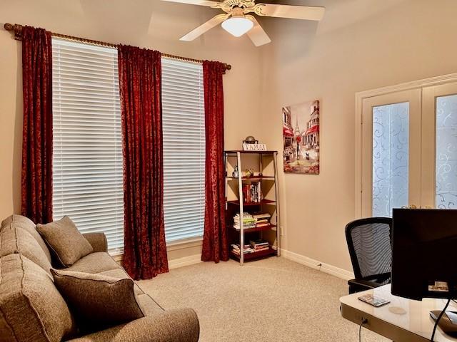 office space with light colored carpet, baseboards, and ceiling fan