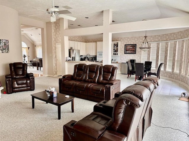 living area with wallpapered walls, ceiling fan, light colored carpet, lofted ceiling, and light tile patterned floors