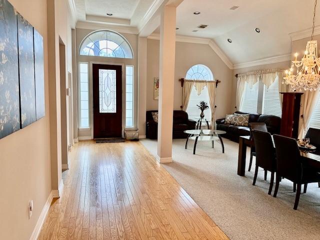 foyer entrance featuring a wealth of natural light, a chandelier, light wood-type flooring, and crown molding