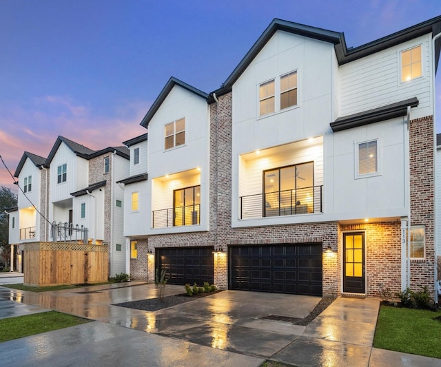 multi unit property featuring a garage, brick siding, driveway, and stucco siding