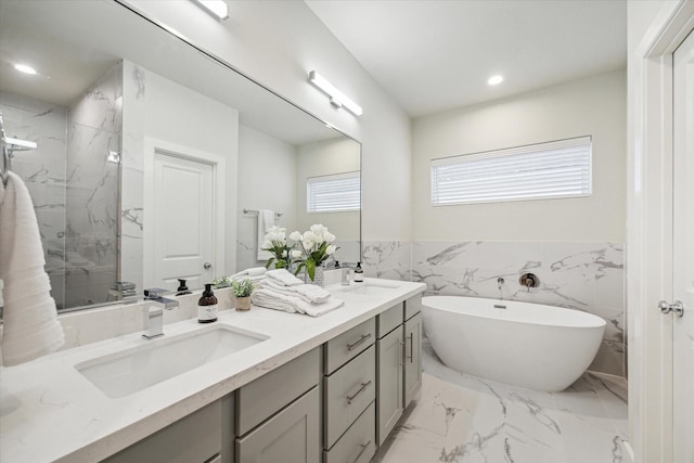 bathroom with a soaking tub, double vanity, recessed lighting, a sink, and marble finish floor