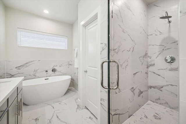 full bathroom with a shower stall, vanity, marble finish floor, and a freestanding tub