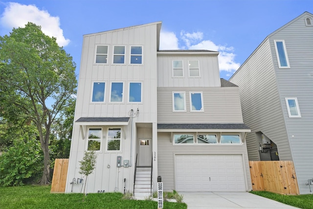 view of front of home featuring board and batten siding, concrete driveway, and fence