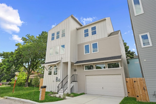 view of front of house with board and batten siding, a front lawn, fence, concrete driveway, and an attached garage