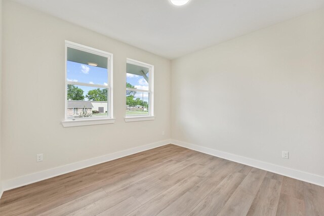 spare room featuring baseboards and light wood finished floors