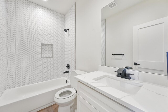 bathroom with visible vents, toilet, wood finished floors,  shower combination, and vanity