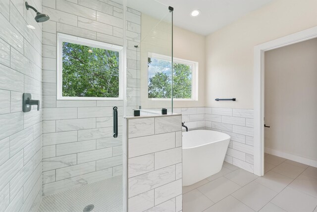 bathroom featuring tile patterned flooring, a stall shower, a freestanding bath, and tile walls