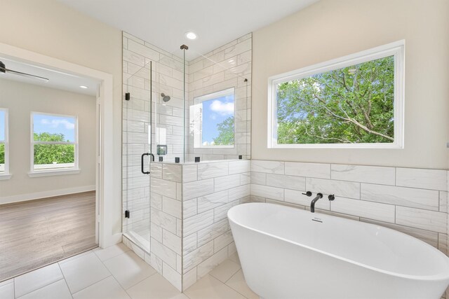 full bathroom with tile patterned floors, a freestanding tub, a stall shower, a ceiling fan, and tile walls