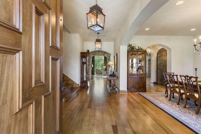 entrance foyer with stairs, wood finished floors, and arched walkways