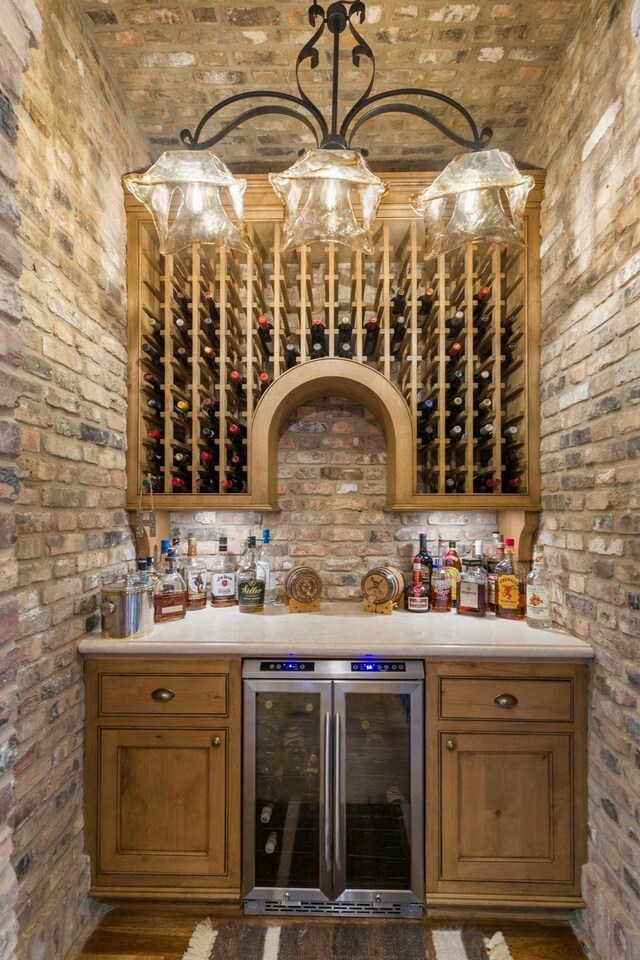 wine room with brick ceiling, beverage cooler, brick wall, and a dry bar