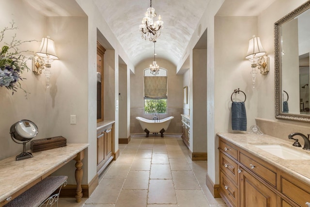 full bathroom featuring lofted ceiling, stone tile floors, an inviting chandelier, baseboards, and a freestanding bath