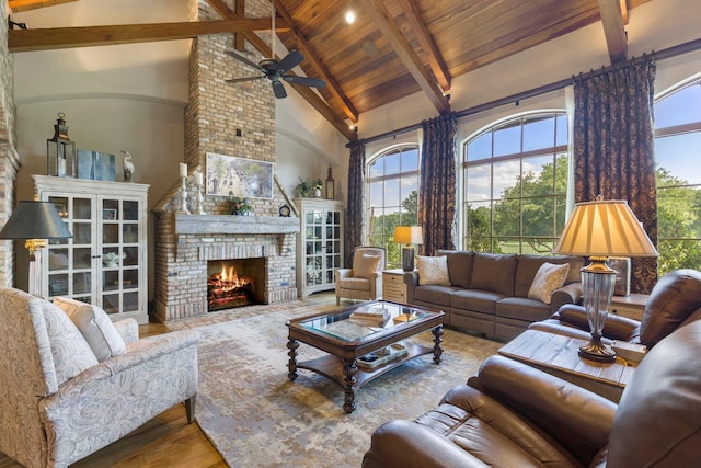 living area with a fireplace, beamed ceiling, wood finished floors, and a healthy amount of sunlight