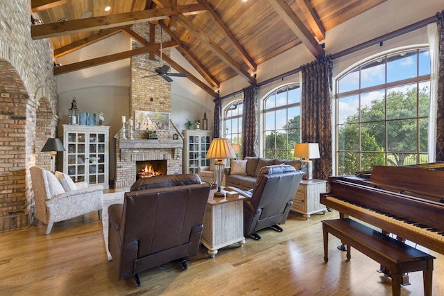 living room with beamed ceiling, a large fireplace, high vaulted ceiling, and wood finished floors