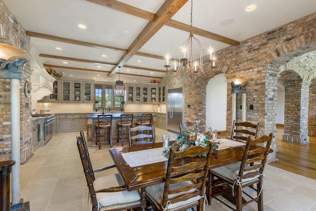 dining space with arched walkways, beam ceiling, brick wall, and decorative columns