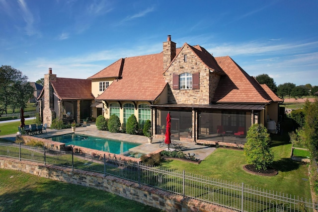 back of property featuring a yard, stone siding, a patio, and a standing seam roof