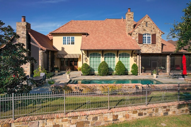 rear view of property featuring a fenced backyard, a chimney, a patio, and a sunroom