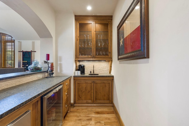 bar with a sink, decorative backsplash, bar, and beverage cooler