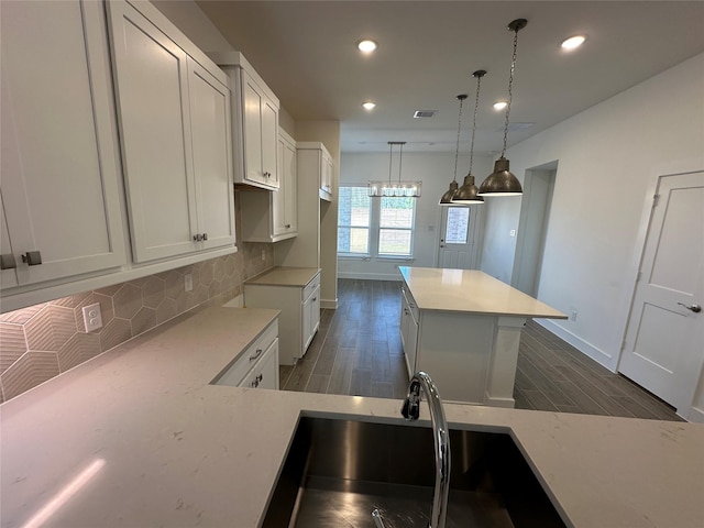 kitchen featuring tasteful backsplash, white cabinetry, a center island, and wood finish floors