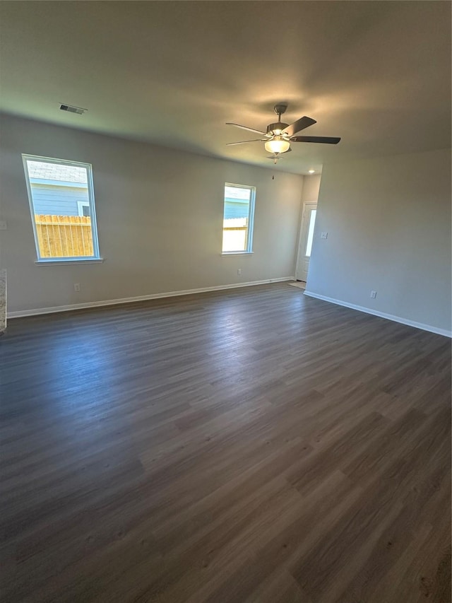 unfurnished room featuring a ceiling fan, visible vents, dark wood-style flooring, and baseboards