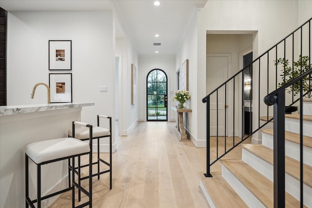 foyer entrance featuring stairway, baseboards, light wood-style flooring, recessed lighting, and ornamental molding