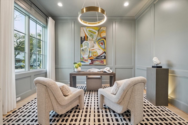 living area with a decorative wall, recessed lighting, and crown molding