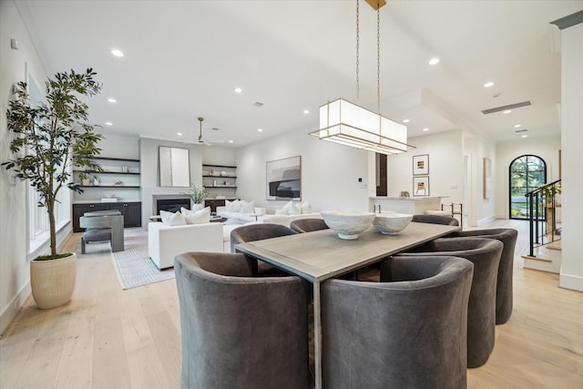 dining space featuring recessed lighting, light wood-style floors, stairs, and a fireplace