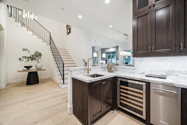 kitchen with wine cooler, dark brown cabinets, a peninsula, and a sink