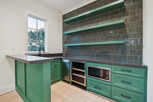 kitchen featuring beverage cooler, open shelves, stainless steel microwave, light wood finished floors, and green cabinetry