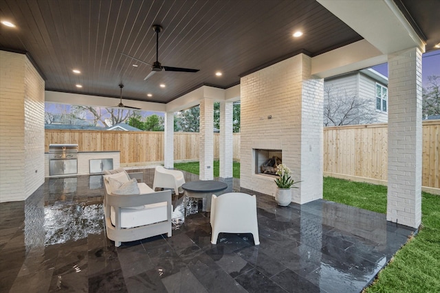 view of patio / terrace with grilling area, an outdoor living space with a fireplace, exterior kitchen, a fenced backyard, and a ceiling fan