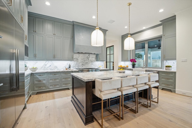 kitchen featuring built in refrigerator, gray cabinetry, light wood-style flooring, light stone countertops, and custom exhaust hood