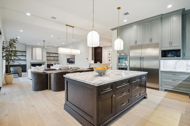 kitchen with visible vents, built in appliances, pendant lighting, and light wood finished floors