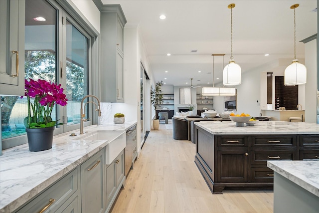 kitchen with light wood finished floors, hanging light fixtures, open floor plan, and a sink