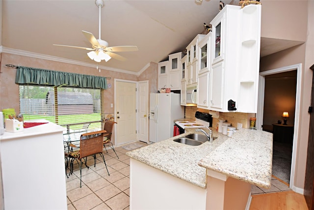 kitchen featuring white appliances, a peninsula, a sink, white cabinetry, and crown molding