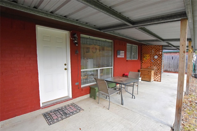 view of exterior entry with outdoor dining space, a patio area, and fence