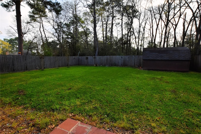 view of yard with an outbuilding, a fenced backyard, and a shed