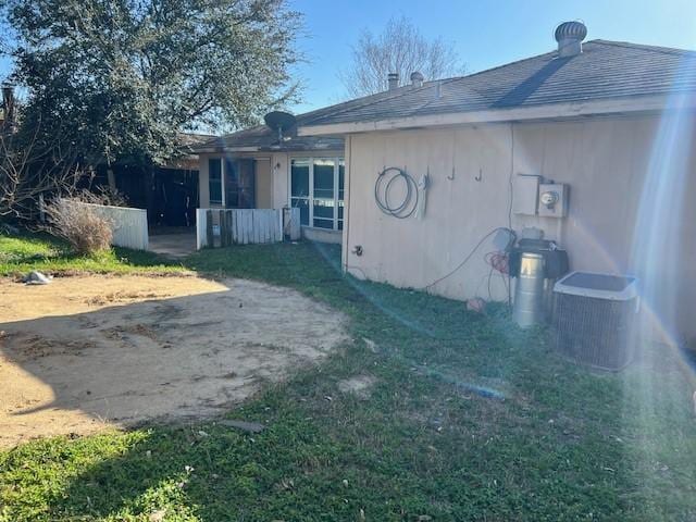 rear view of house featuring a patio area, central air condition unit, stucco siding, and a yard