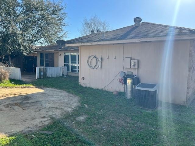 back of property with a yard and central AC