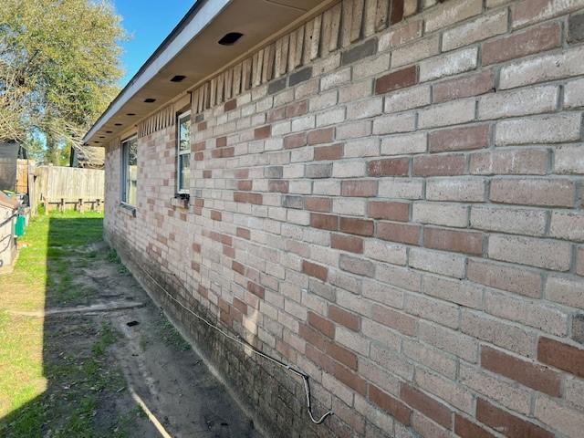 view of property exterior featuring brick siding and fence