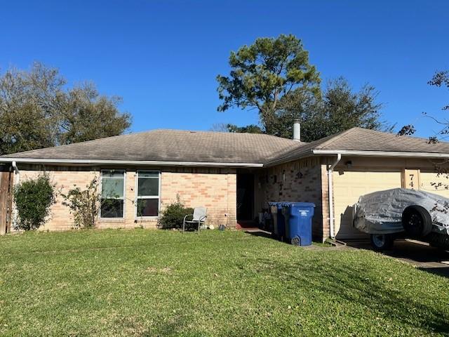 back of house with a garage, a lawn, and brick siding