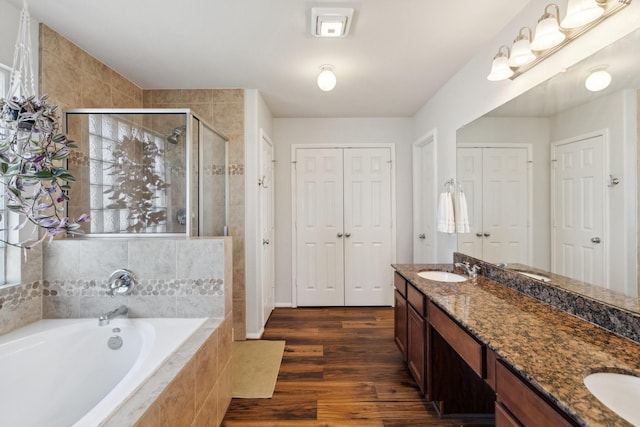 full bath featuring double vanity, a sink, a shower stall, a closet, and a garden tub