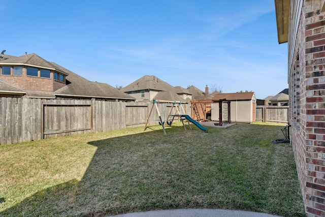 view of yard featuring an outbuilding, a playground, and a fenced backyard