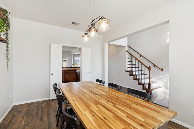 unfurnished dining area with visible vents, a sink, dark wood finished floors, stairway, and baseboards