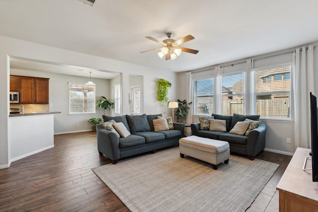 living room featuring baseboards, dark wood-style flooring, and ceiling fan