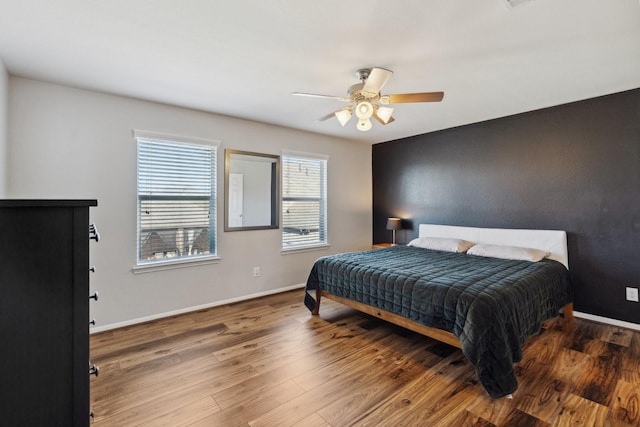 bedroom with ceiling fan, baseboards, and wood finished floors