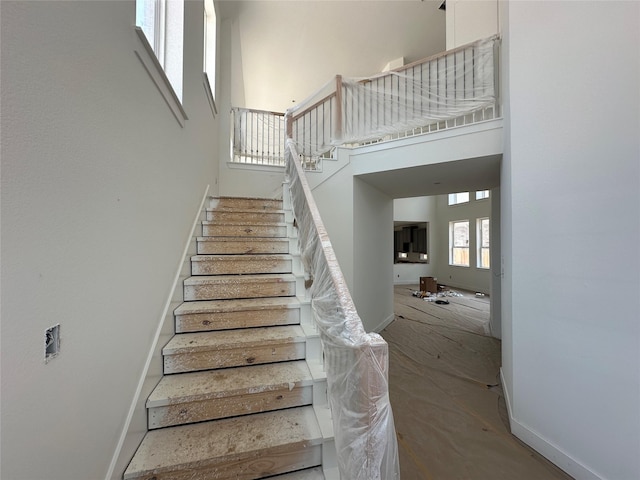 staircase with a high ceiling and baseboards